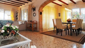A spacious living area with a dining table, chairs, a sofa, and a coffee table with flowers. - Portichol by Interhome (Jávea)