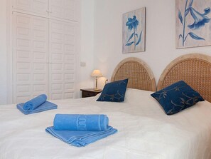 A hotel room with a bed, two pillows, a lamp, and artwork on the wall.