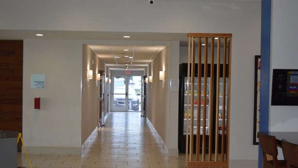 A hotel corridor with a wooden floor, a reception desk, and a vending machine. - Holiday Inn Express & Suites Liberal by IHG (Liberal)