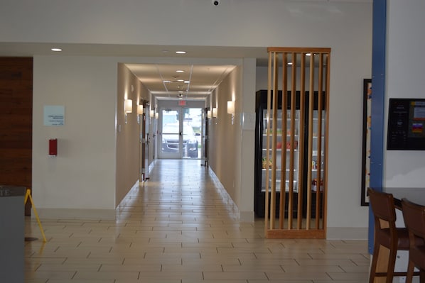 A hotel corridor with a wooden floor, a reception desk, and a vending machine.
