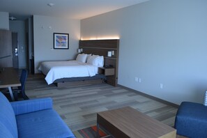 A hotel room with a bed, bedside table, lamp, and a small desk with a chair. - Holiday Inn Express & Suites Liberal by IHG (Liberal)