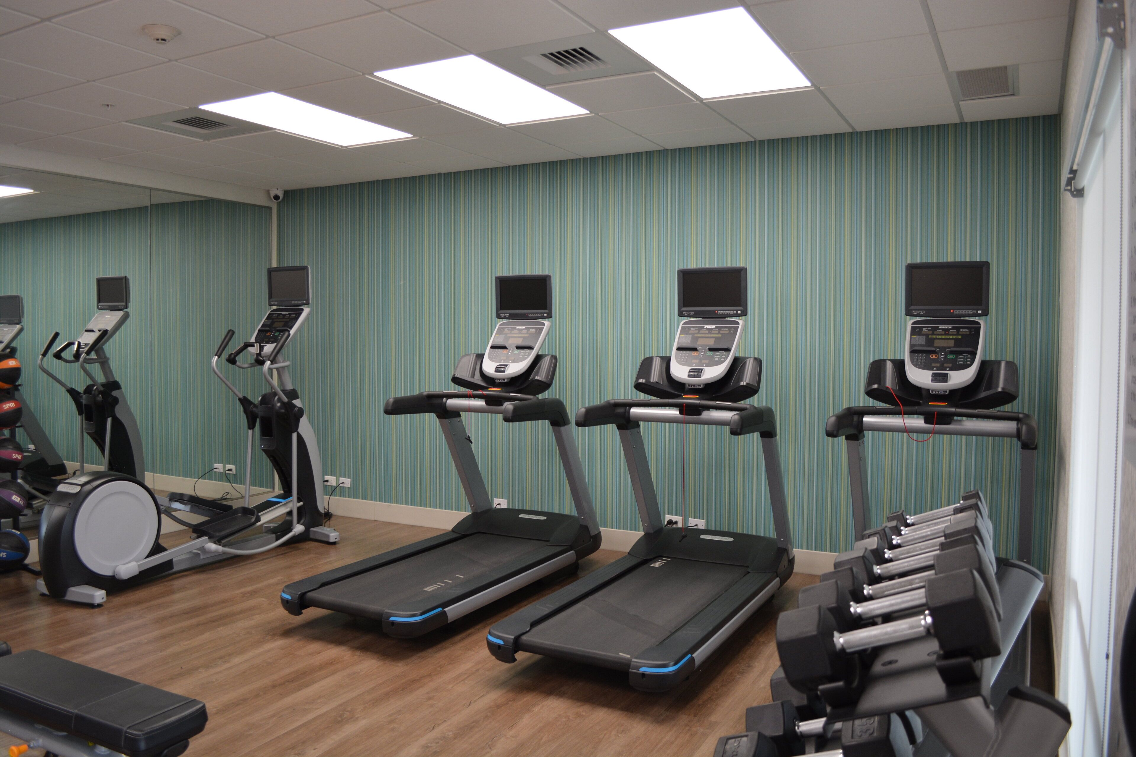Un centre de remise en forme équipé de tapis de course, de vélos elliptiques et d’un appareil d’aviron.