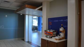 A modern office space with a reception area, a blue wall with directional signage, and a counter with various items.
