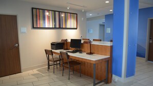 A reception desk with a computer, two chairs, and a framed artwork on the wall. - Holiday Inn Express & Suites Liberal by IHG (Liberal)