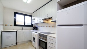 A compact kitchen with a dishwasher, washing machine, stove, and refrigerator. - Escorxador by Interhome (L'Escala)