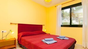 A single-bed room with a red headboard, a bedside lamp, and two towels on the bed. - Escorxador by Interhome (L'Escala)