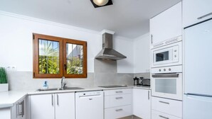 A modern kitchen with white cabinets, a dishwasher, a stove, and a microwave.