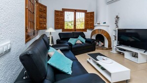 A living room with a black leather sofa, a white coffee table, a fireplace, and a television.