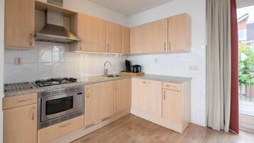 Een koelkast, een magnetron, een vaatwasser, kookgerei, borden en bestek