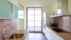 A modern kitchen with stainless steel appliances, a double sink, and a sliding door leading to a balcony. - Diagonal Mar by Interhome (Barcelona)