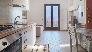 A modern kitchen with a gas stove, white cabinets, and a large window with a view of a mountainous landscape. - La Rocca by Interhome (Castelveccana)