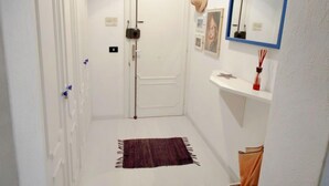 A narrow hallway with a white door, a small rug, and a mirror on the wall. - Francesca by Interhome (Camogli)