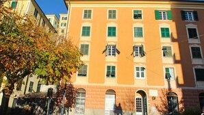 A multi-story building with a yellow facade, green shutters, and a central entrance with a white door. - Francesca by Interhome (Camogli)