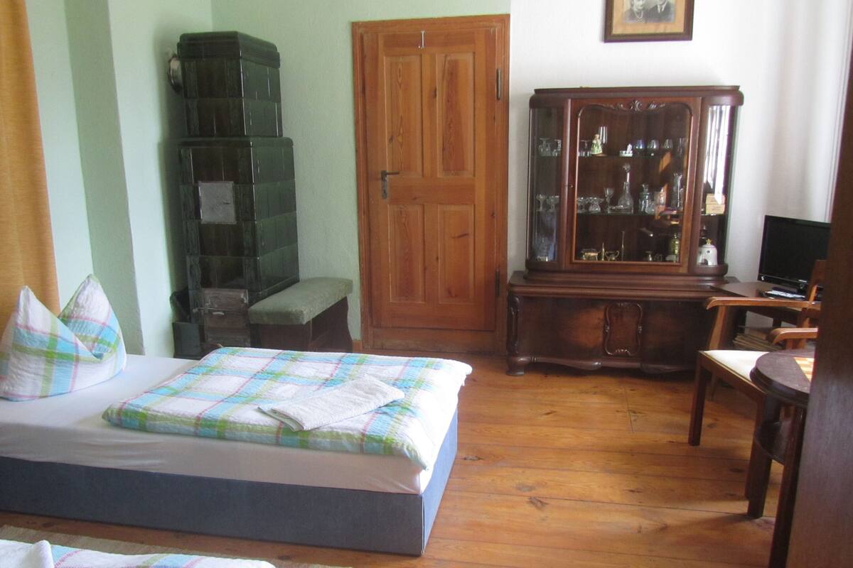 Ein Schlafzimmer mit einem Bett, einem Holzkasten, einem Fernseher und einer Bank.