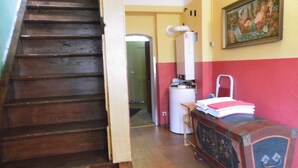 A staircase leading to a room with a water heater, a radiator, and a painting on the wall.