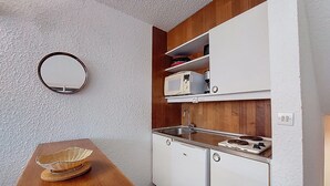 Eine kleine Küche mit weißen Schränken, einer Holz Arbeitsplatte, einer Mikrowelle, einer Kaffeemaschine und einem Spülbecken.