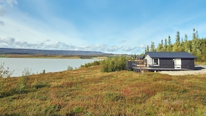 Una cabaña junto a un lago con una vista despejada del paisaje circundante.