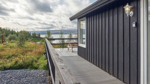 Una terraza de madera con vistas a un lago y montañas.