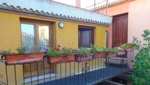 A balcony with flower planters, a yellow wall, and a wooden door. - B&B Porto Frailis (Tortoli)