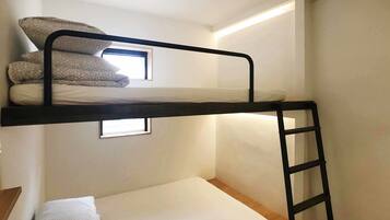A bunk bed with a ladder, a window, and a small bedside table.