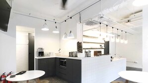 Una cocina moderna con una isla central, iluminación colgante y un comedor con taburetes.