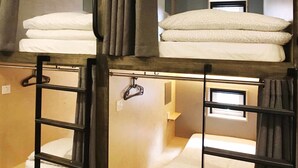 Habitación con literas de dos niveles, cada una con una escalera y un perchero.