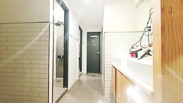 A hotel corridor with a tiled floor, a door marked "TOILET," and a counter with a mirror and some items on it.