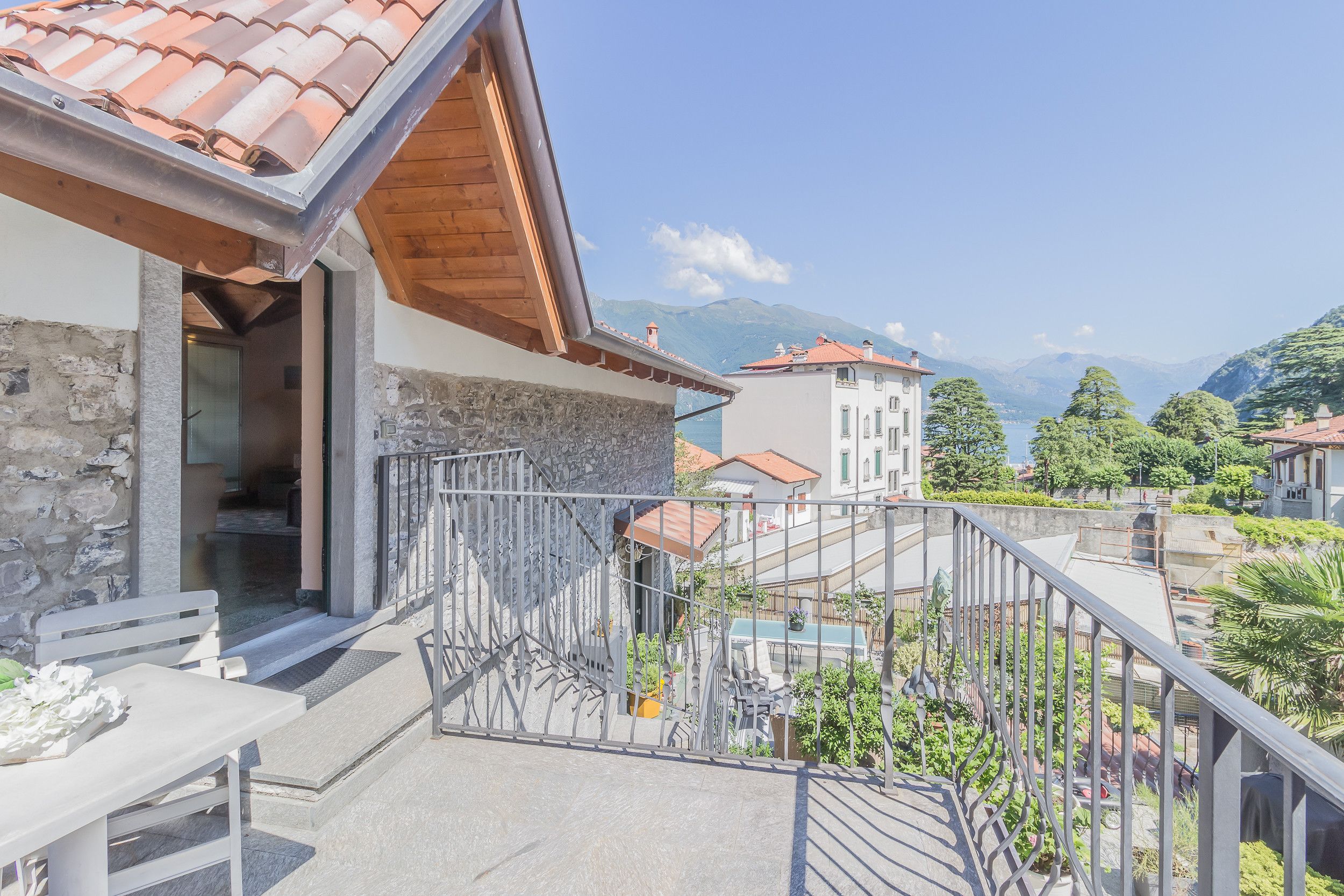 Un balcone con parete in pietra, ringhiera in metallo e vista sulle montagne.