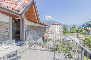 Un balcon doté d’un mur en pierre, d’une rambarde en métal et offrant une vue sur les montagnes.