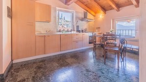 Une cuisine avec des meubles en bois, un sol en marbre et un coin repas comprenant une table et des chaises.