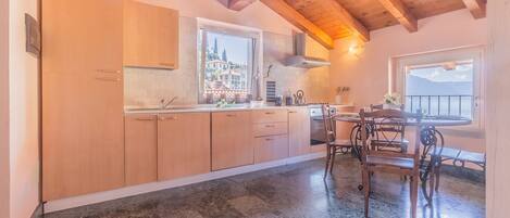 A kitchen with wooden cabinets, a marble floor, and a dining area with a table and chairs.