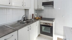A modern kitchen with white cabinets, stainless steel appliances, and a black countertop. - 4 Bed-Sleeps 6-Garden-Balcony-Pets (Alcalá de Henares)