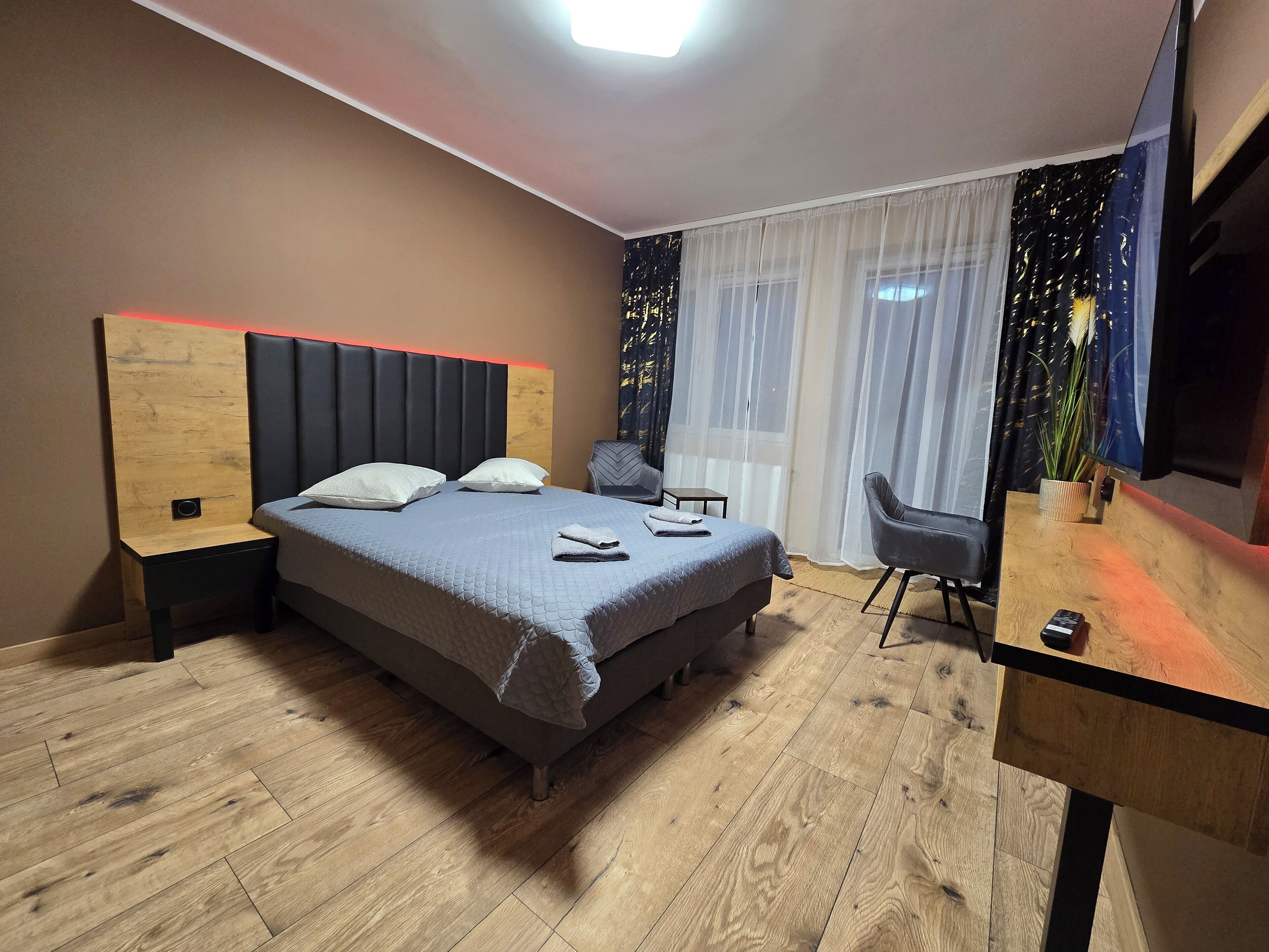 A modern bedroom with a bed, bedside tables, a desk, and a chair.