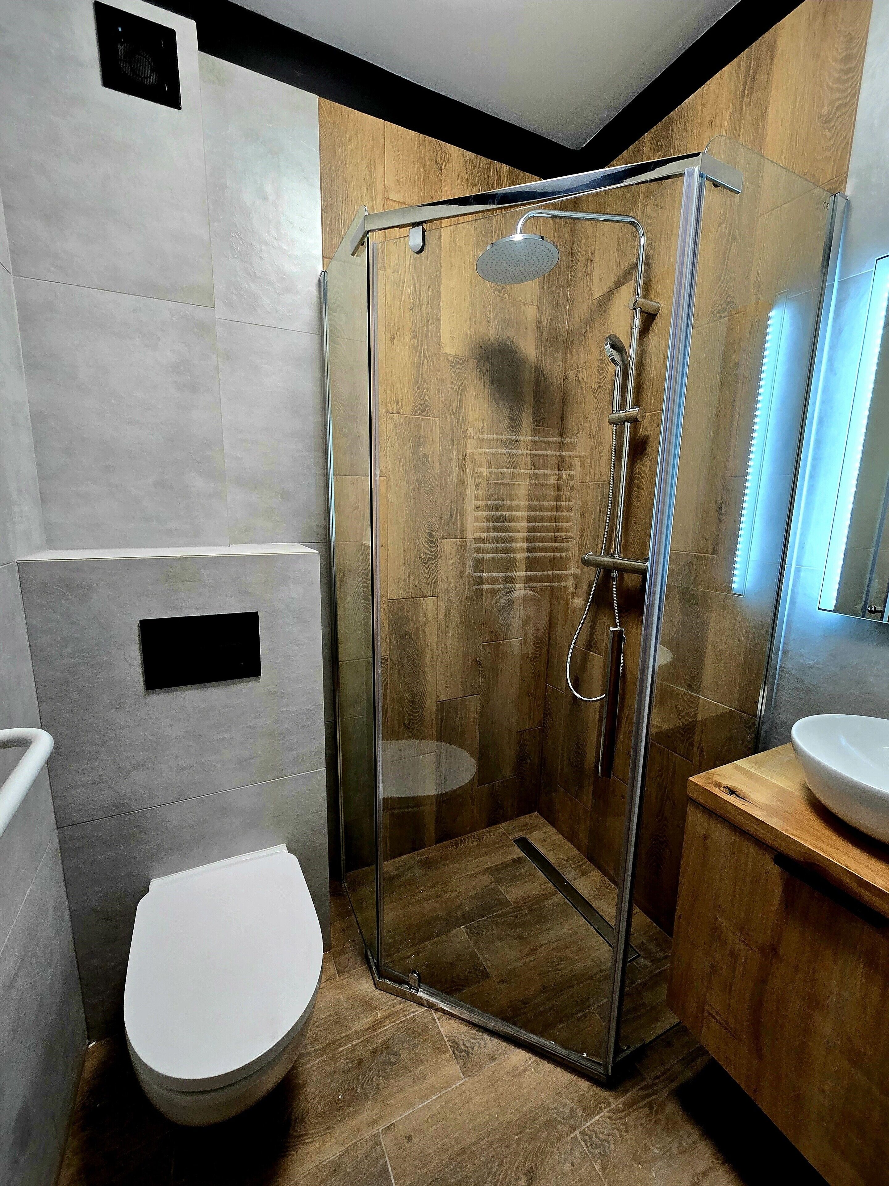 Ein modernes Badezimmer mit einer Duschkabine, einer Toilette und einem Waschbecken.