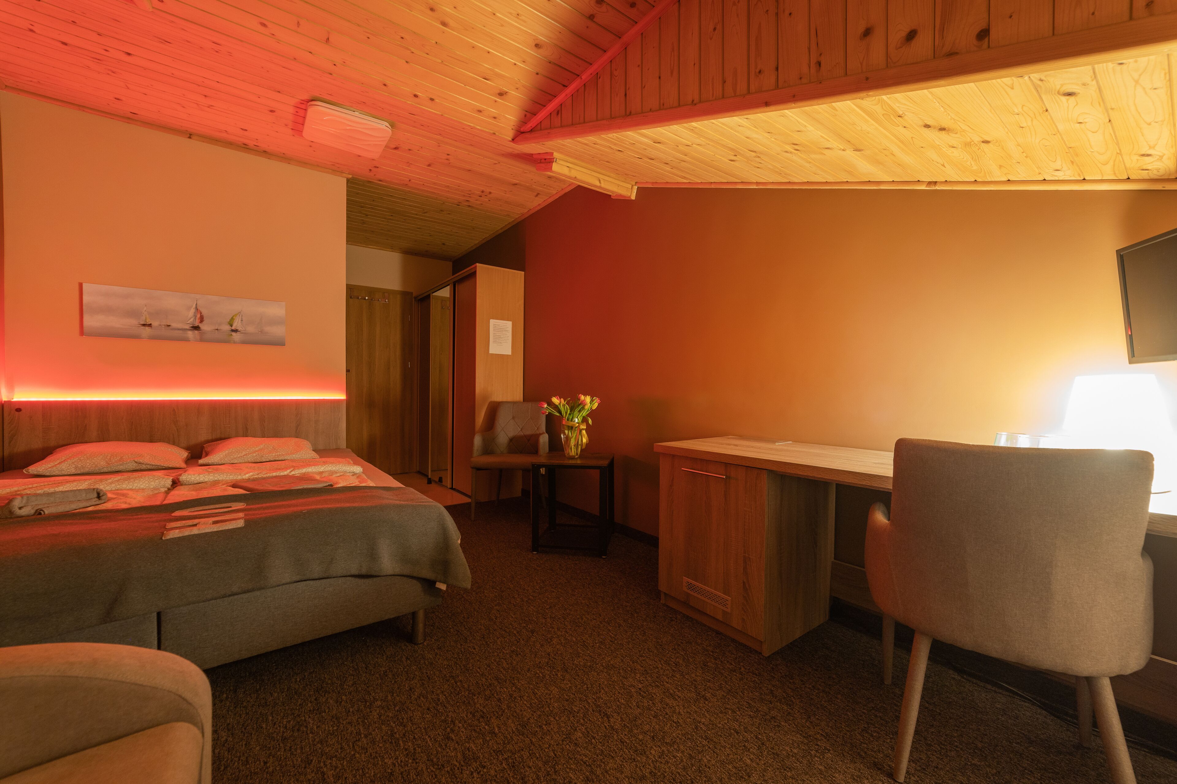 Una habitación de hotel con cama, escritorio, silla y una mesita con un jarrón.