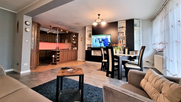 Un soggiorno moderno con un divano, un tavolino da caffè e una televisione sullo sfondo.