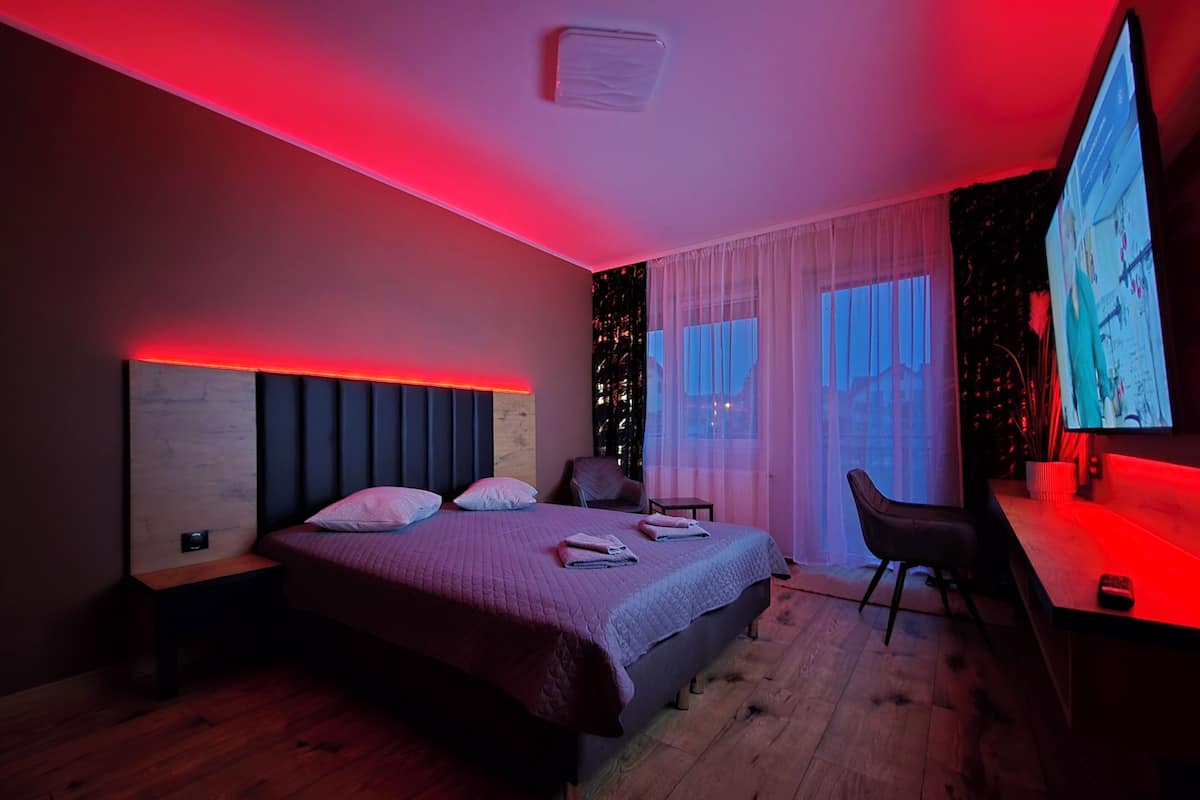 A modern hotel room with a large bed, a desk, and a TV.