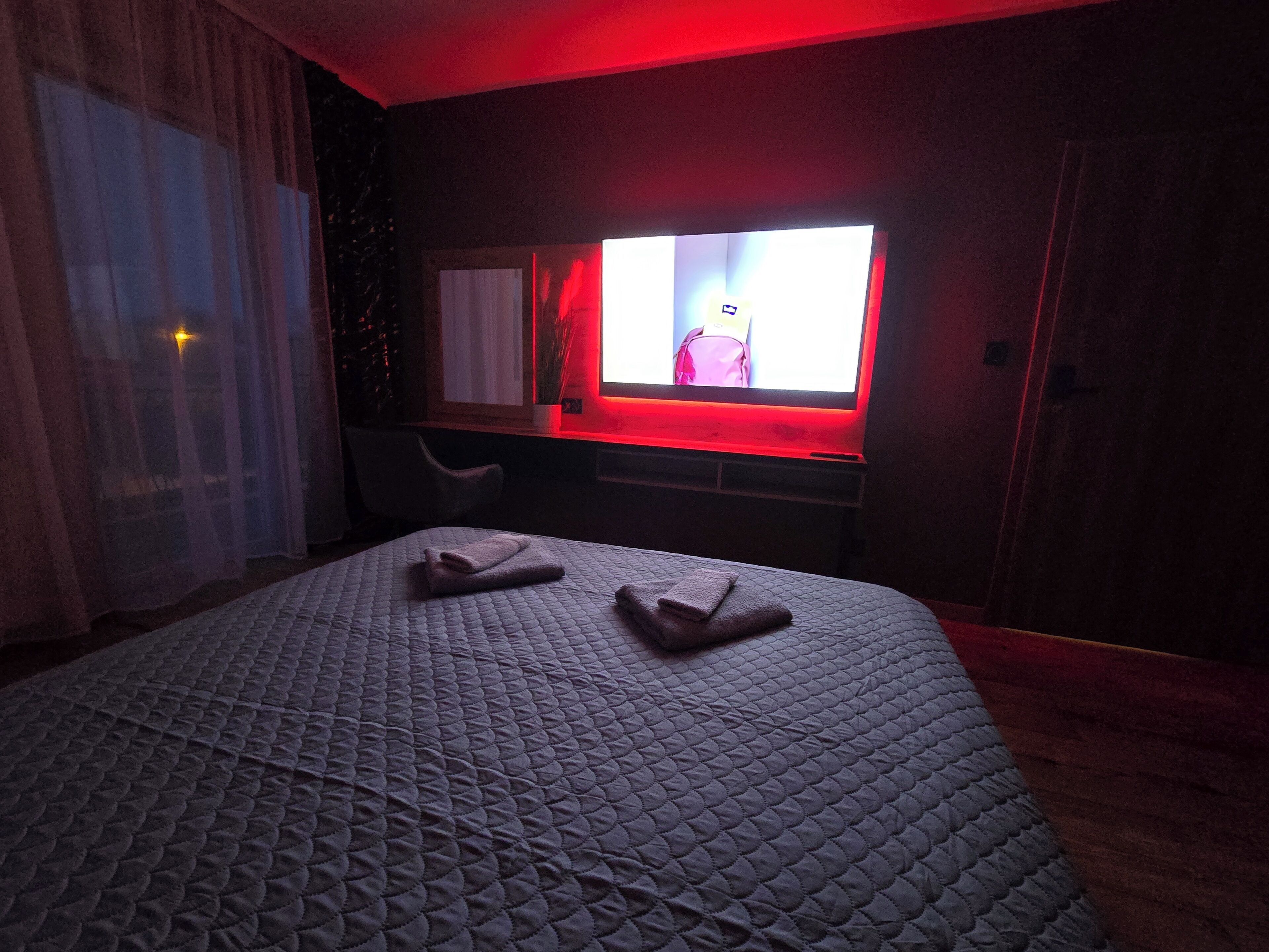 A hotel room with a bed, a desk, and a TV.
