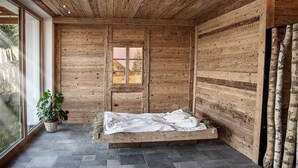 Une pièce rustique en bois, avec un lit, une fenêtre et une plante en pot.