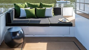 Un pont de bateau doté d’un espace salon avec des coussins et une petite table.