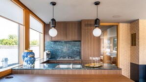 Une cuisine moderne avec des meubles en bois, un plan de travail en marbre et des luminaires suspendus.