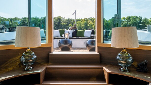 Un intérieur moderne donnant sur un balcon, avec un canapé agrémenté de coussins et deux lampes posées sur une table en bois.