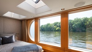 Une chambre avec une grande fenêtre, un puits de lumière et une vue sur une rivière.