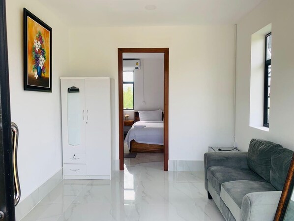 A modern bedroom with a bed, a wardrobe, and a grey sofa. - Prek Kdat Resort (Kampot)