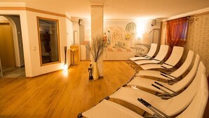 Una habitación con piso de madera, un mostrador de recepción, un mural y varias sillas reclinables.