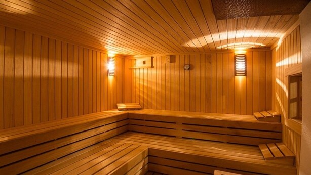 Una sauna de madera con bancos y luces fijadas a la pared.