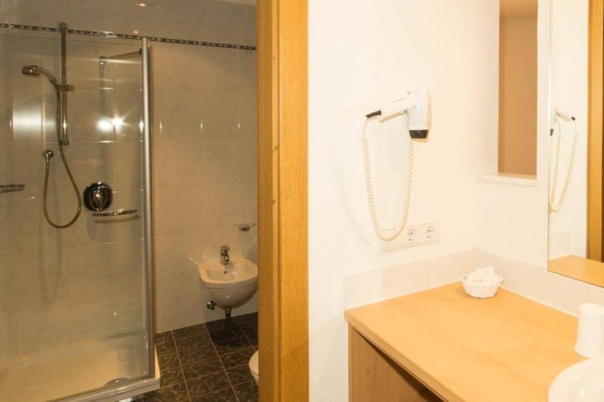 Un baño con ducha de vidrio, lavabo con espejo e inodoro.