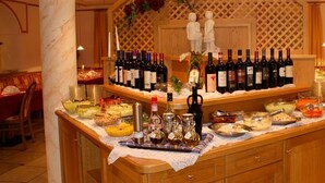 Disposición de mesa buffet con diversos alimentos y botellas de vino.