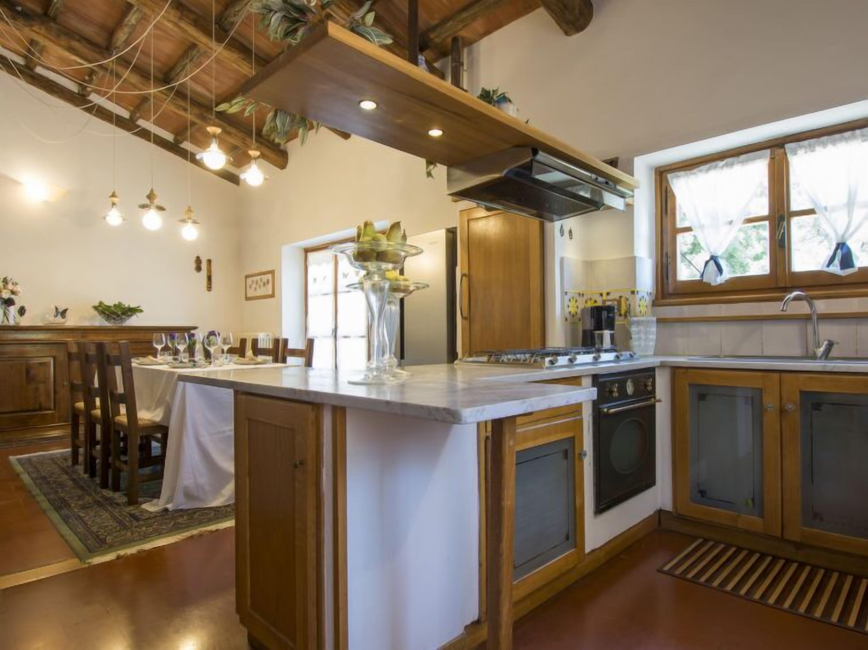 A kitchen with wooden cabinets, a central island, and a dining area with chairs and a table.
