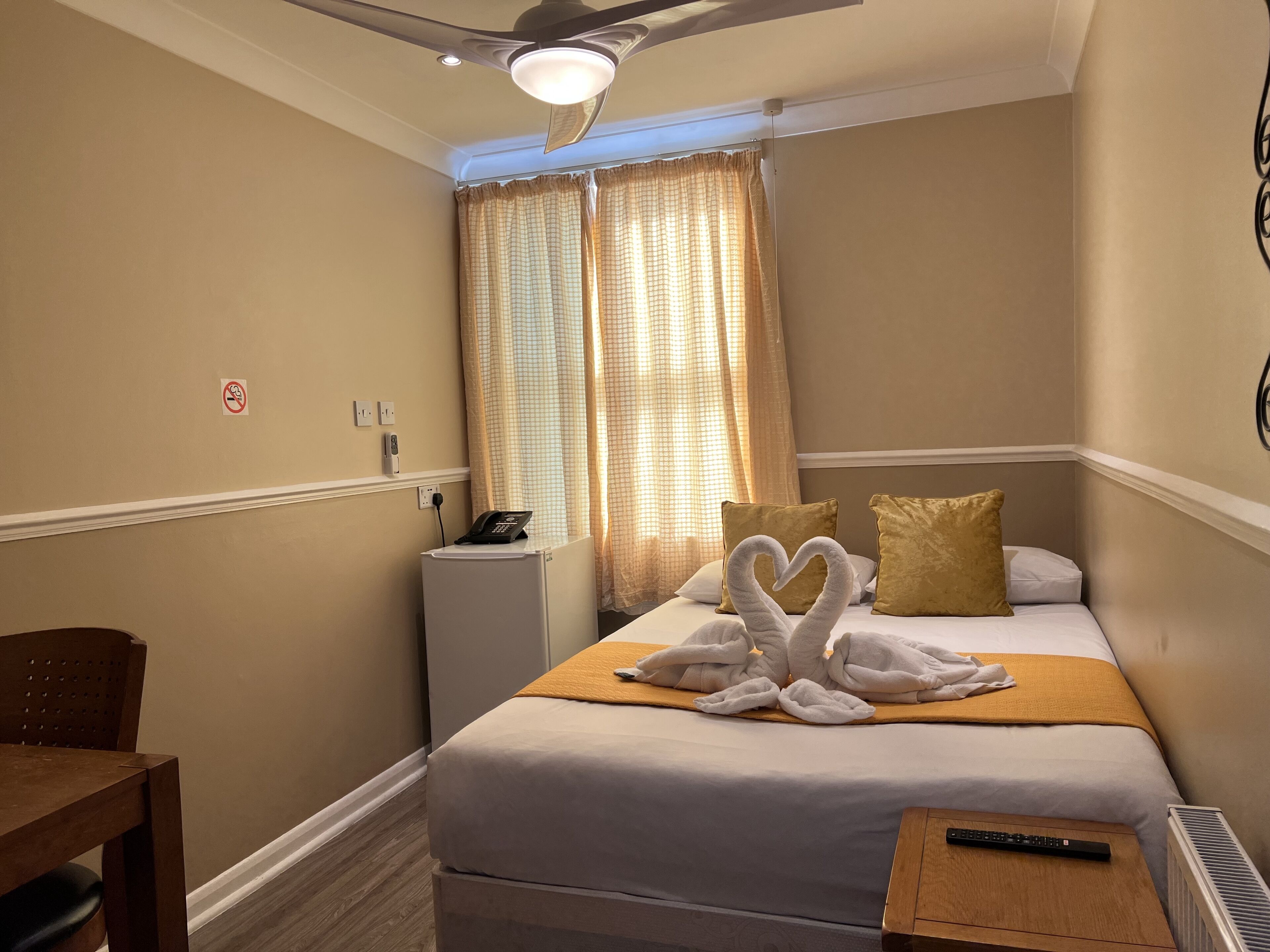 Une chambre d’hôtel équipée d’un lit, d’un bureau, d’une chaise, d’un téléphone et d’un radiateur.